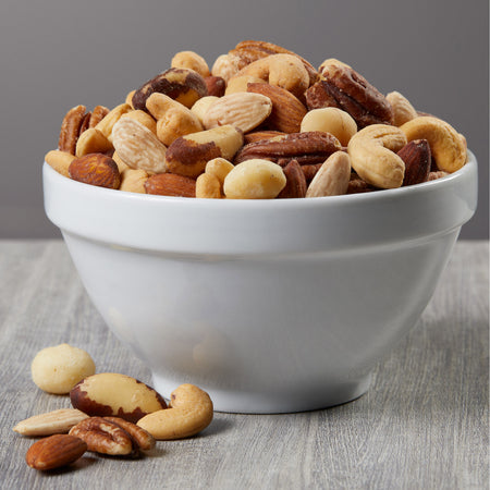 White bowl filled with a mix of nuts on a gray surface