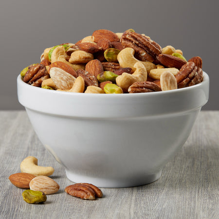 White bowl filled with a mix of nuts on a wooden surface