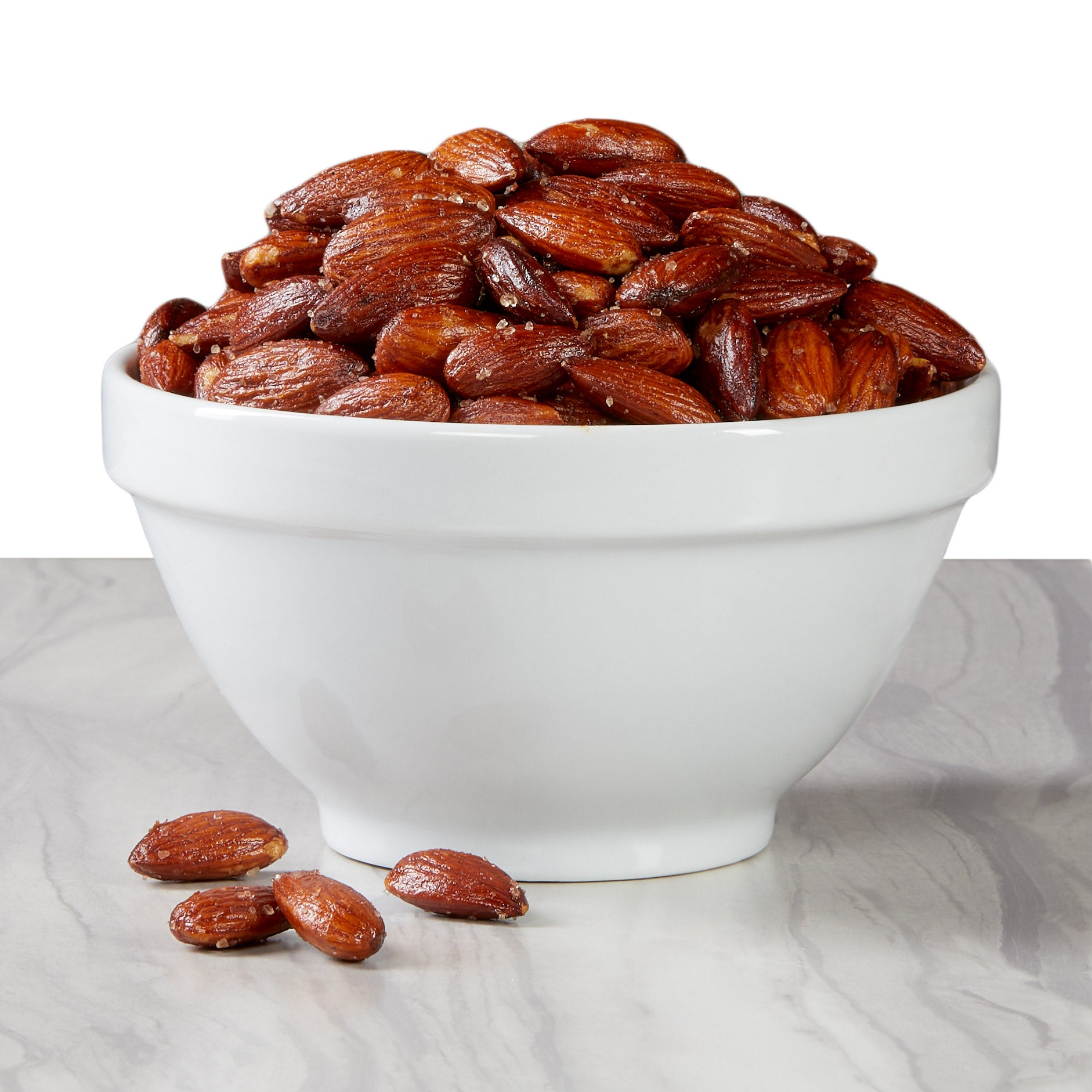 White bowl filled with roasted almonds on a marble surface