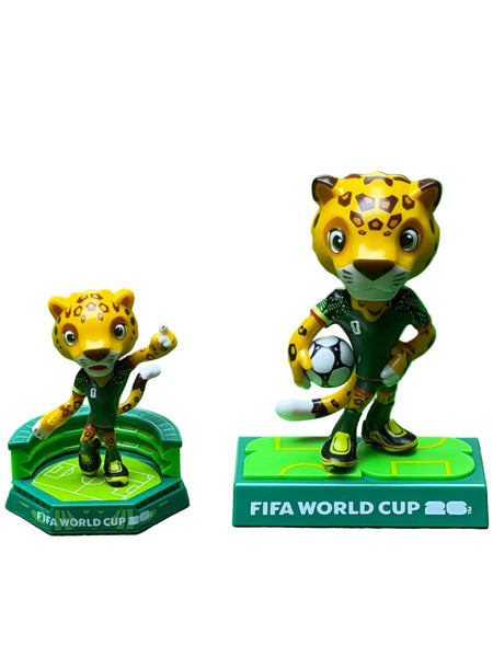 Two FIFA World Cup 2026 mascot figurines on a green background