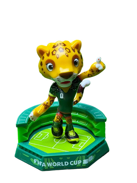 Toy figure of a leopard mascot on a FIFA World Cup base against a green background