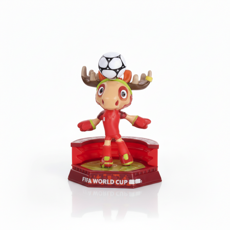 Figurine with a soccer ball on its head, wearing a red outfit and green hat, standing on a red base with 'FIFA World Cup' text.
