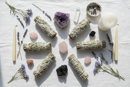Elegant overhead flat lay of white sage smudge sticks with crystals and candles spiritual aesthetic